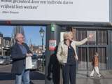 Man en vrouw staan voor het citatenbord op het kerkplein in Appingedam.