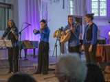 Band op podium met in Nicolaikerk bij aftrap 80 jaar vrijheid. Er word gitaar en viool gespeeld.