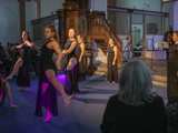 Dansgroep op podium met microfoon in Nicolaikerk bij aftrap 80 jaar vrijheid. In de achtergrond speelt iemand viool.