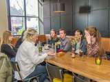 Mensen zitten en praten gezellig met drinken bij de Pelikaan-uitreiking.