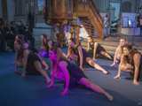 Dansgroep op podium met microfoon in Nicolaikerk bij aftrap 80 jaar vrijheid. Alle dansers doen dezelfde pose.
