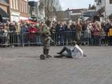 Verklede mensen praten op kerkplein bij Living History Appingedam. Één van de mannen heeft de laars van de andere vast.