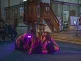 Dansgroep op podium met microfoon in Nicolaikerk bij aftrap 80 jaar vrijheid. In de achtergrond speelt iemand viool.