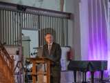 Man spreekt op podium in Nicolaikerk bij aftrap 80 jaar vrijheid.