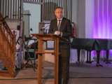 Man spreekt op podium in Nicolaikerk bij aftrap 80 jaar vrijheid.