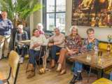 Mensen zitten gezellig met koffie aan tafel bij de Pelikaan-uitreiking.