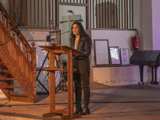 Vrouw spreekt op podium in Nicolaikerk, aftrap 80 jaar vrijheid.