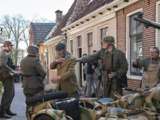 Verklede mensen en soldaten staan op straat met oude oorlogsmotor bij Living History Appingedam.