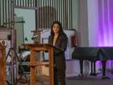 Vrouw spreekt op podium in Nicolaikerk, aftrap 80 jaar vrijheid.