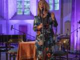 Vrouw op podium met microfoon in Nicolaikerk, aftrap 80 jaar vrijheid.