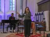 Vrouw op podium met microfoon in Nicolaikerk, aftrap 80 jaar vrijheid. Piano op de achtergrond.