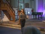 Vrouw op podium met microfoon in Nicolaikerk, aftrap 80 jaar vrijheid.